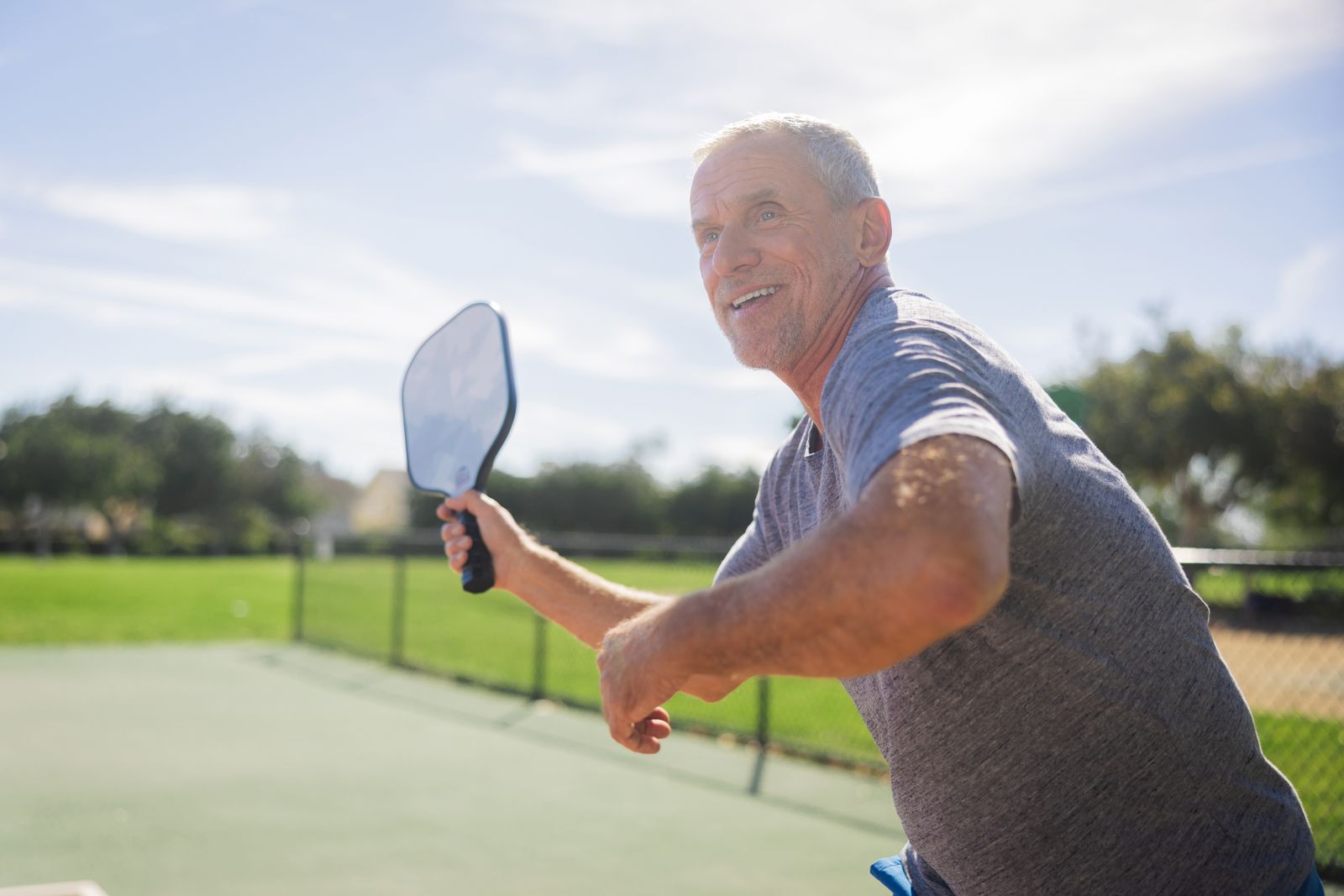 Player reaching for a shot with a pickleball paddle on a sunny outdoor court